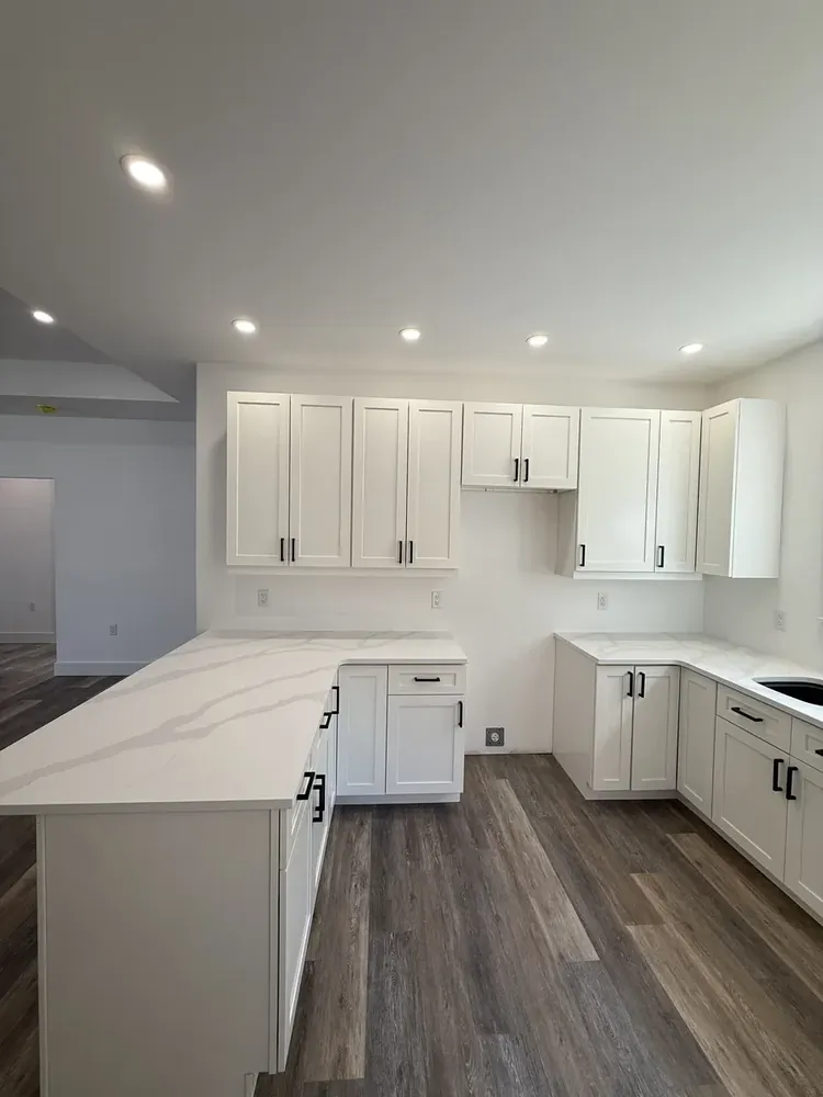 A Wildawbren kitchen with white shaker cabinets, marble-veined quartz waterfall counters, and a wide-plank wood floor