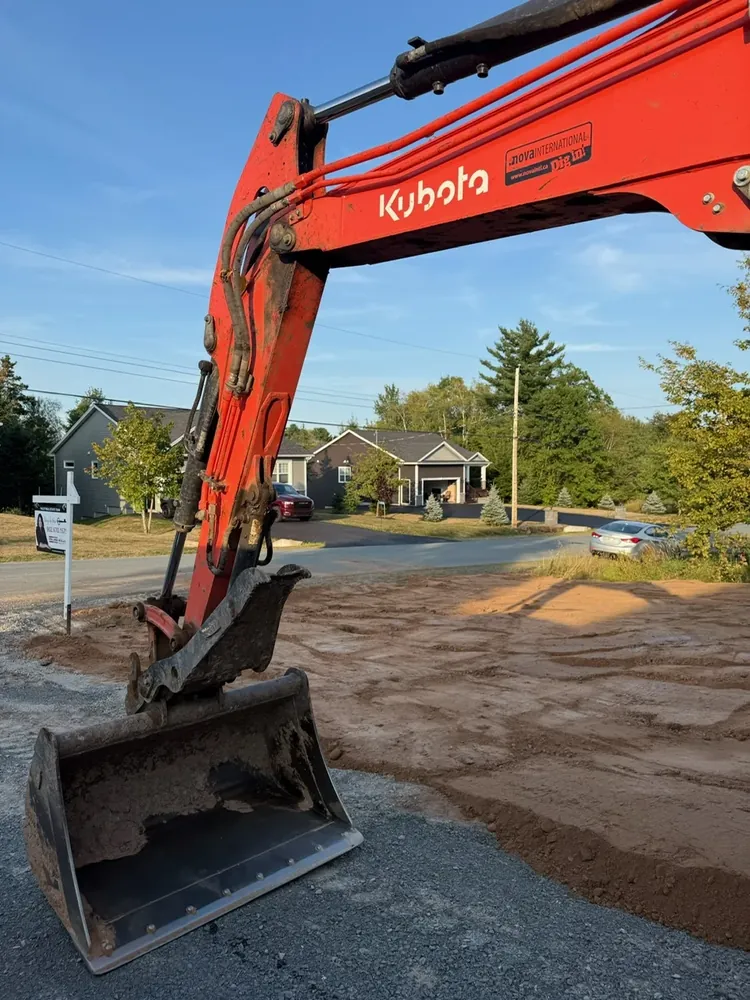 A Wildawbren orange Kubota mini excavator with the bucket at full reach, scooping graded earth on a residential lot in Hants County
